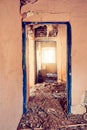 Interior of a desolated old rural house with light pink cracked walls, detached door