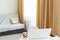 Interior detail view of a white laptop computer at home in living room with coffee or tea in cup on table, workspace near a window Royalty Free Stock Photo