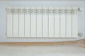 Just installed a new steel heating radiator. Full view of a white radiator against a cream wall . Interior detail. White metal Royalty Free Stock Photo