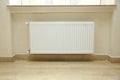 Just installed a new steel heating radiator. Full view of a white radiator against a cream wall . Interior detail. White metal Royalty Free Stock Photo