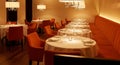 Elegant Restaurant Interior with Round Tables Set for Dining and Orange Booth Seating setting Royalty Free Stock Photo
