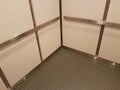 Interior of elevator with grey floor and metal bars and white walls