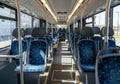 Interior of an empty public bus with rows of blue cushioned seats featuring a geometric pattern. Royalty Free Stock Photo