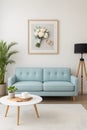 Elegant interior showcasing light blue sofa complemented by framed floral artwork decorative plant round coffee table and stylish Royalty Free Stock Photo