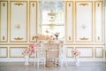 Interior with gold stucco, mirror, flowers in vases and decorative fireplace.