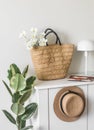 The interior of the hallway is a white wooden chest of drawers with a straw basket, hat, flowers. Scandinavian style Royalty Free Stock Photo