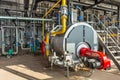 Interior of an industrial boiler room with boilers, many pipes, valves and sensors