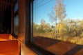 Interior of intercity train with orange plastic seats, window view of a rural autumn landscape Royalty Free Stock Photo