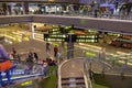 Interior of international airport in Doha, Qatar, with flight signs and passengers. Gates information boards with arrows.