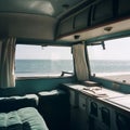 Interior of large caravan auto trailer, outside window sees beautiful natural landscape sea and beach,