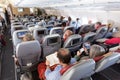 Interior of large commercial airplane with passengers on their seats during flight. Royalty Free Stock Photo
