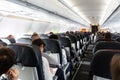 Interior of large commercial airplane with passengers on their seats during flight. Royalty Free Stock Photo