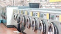 Interior of laundromat with multiple washing machines standing in perfect order Royalty Free Stock Photo