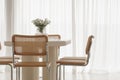 Interior of light dining room with white table, rattan chairs. Japandi interior concept.