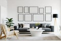 Interior living room, gallery wall poster frames mockup in white room with wooden furniture and lots of green plants. Royalty Free Stock Photo