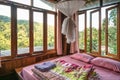 Interior of local homestay with bed, mosquito net, blanket and wooden window among the tropical rainforest on vacation