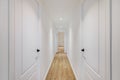 Interior of long narrow hallway with closed doors, wooden floor and white walls in apartment designed in minimal style Royalty Free Stock Photo