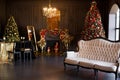 Interior of luxury dark living room with fireplace, comfortable sofa and chandelier decorated with Christmas tree and Royalty Free Stock Photo