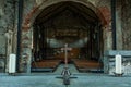 Interior of a medieval ruined church with altar cross and candles and the prayer benches