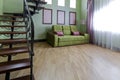 Interior with a metallic black staircase with wooden steps and a green sofa in the living room