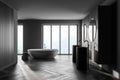 Interior of modern bathroom with dark gery wooden walls, concrete floor, two sinks with two round mirrors above it and comfortable