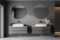 Interior of modern bathroom with dark gray walls, concrete dark floor, sink with round mirror and cabinets. Concept of spa Royalty Free Stock Photo