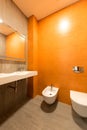 interior of modern bathroom in orange and white colors with toilet Royalty Free Stock Photo