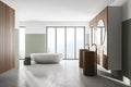 Interior of modern bathroom with white and wooden walls, concrete floor, two sinks with two round mirrors above it and comfortable