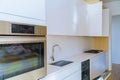 Interior of modern kitchen with appliances on stove top, marble counter with kitchen white cabinets