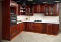 Interior of modern kitchen in classic style with golden elements cherry alder wood cabinetry with built-in appliances electric or Royalty Free Stock Photo