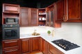 Interior of modern kitchen in classic style with golden elements cherry alder wood cabinetry with built-in appliances electric or Royalty Free Stock Photo