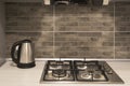 Interior of a modern kitchen. Close-up of electric kettle and gas hob on grey tile backsplash Royalty Free Stock Photo