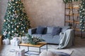 Interior of modern living room with comfortable sofa decorated with Christmas tree and gifts