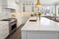 Interior of modern luxurious kitchen classic style. White cabinets with gilded handles, kitchen island with white marble