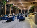 Interior of modern luxury restaurant in a hotel, during evening. Large windows, blue armchairs, greenhouse. Gornoaltaysk