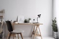 Interior of modern office with wooden desk and chair. Minimalistic style. White walls.