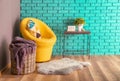 Interior of modern room with basket, armchair and houseplant on table near color wall Royalty Free Stock Photo