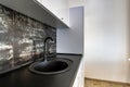 Interior of modern spacious kitchen with white contemporary furniture, black ceramic tiles on the wall and dark granite sink with Royalty Free Stock Photo