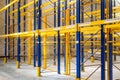 Interior of a modern warehouse storage with empty rows and high blue yellow steel shelves