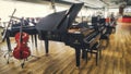 Interior of a music shop with various instruments including a concert grand piano and cello