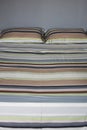 Interior natural light shot of a colorful, striped bed linen with two pillows, a duvet with textile cotton sheets on a king size Royalty Free Stock Photo