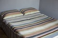 Interior natural light shot of a colorful, striped bed linen with two pillows, a duvet with textile cotton sheets on a king size Royalty Free Stock Photo