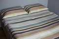 Interior natural light shot of a colorful, striped bed linen with two pillows, a duvet with textile cotton sheets on a king size Royalty Free Stock Photo