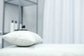 The interior of the office of a beauty specialist. A white couch with a pillow stands against the background of a shelf