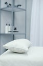 The interior of the office of a beauty specialist. A white couch with a pillow stands against the background of a shelf