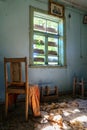 The interior of an old abandoned uninhabited house. An old wooden chair in a dirty, untidy room. Boarded up windows with wooden Royalty Free Stock Photo