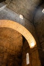 Interior of an old cathedral / church in Europe. Arches, vaulted ceilings and walls lit by lamps and windows backlit by the sun