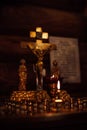 Interior of orthodox church with candles on stand with candlesticks burning on altar in front of crucifixion of Jesus.