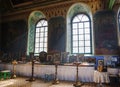 The interior of an Orthodox church with large windows, painted walls.