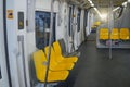 Interior of a passenger car of a commuter train. Yellow plastic seats and chrome handrails inside an electric train Royalty Free Stock Photo